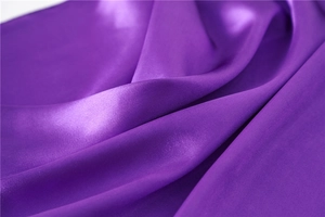 Detailed view of the smooth purple satin fabric with elegant silk texture and soft folds