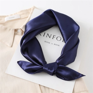 Close-up of a navy blue silk satin square scarf tied elegantly on a white shirt