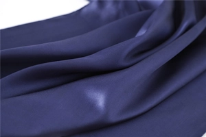 Close-up of deep blue silky square scarf fabric with elegant draped texture and soft sheen
