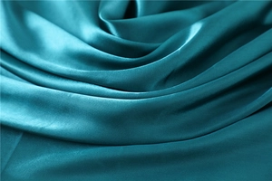 Detailed view of teal satin fabric with silky texture and elegant draping effect