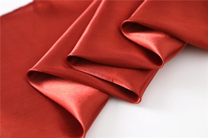 Macro shot of dark red satin scarf fabric showing luxury silk texture and smooth drape