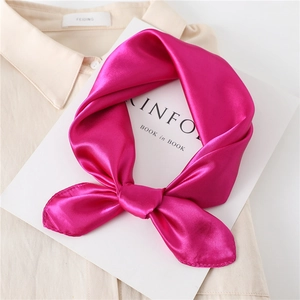 Detail of fuchsia silk satin neckerchief tied in a bow over a magazine and shirt