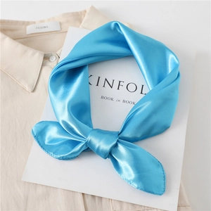 Close-up of knotted sky blue satin square scarf with premium silky texture on magazine