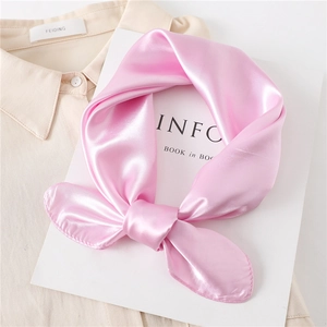 Detail view of a knotted pink silk satin scarf with a smooth finish on a beige shirt