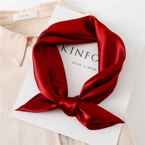 Close-up of deep red satin neckerchief tied in an elegant bow on a magazine