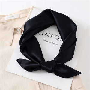 Close-up of black satin silk scarf tied in a bow on a beige shirt collar
