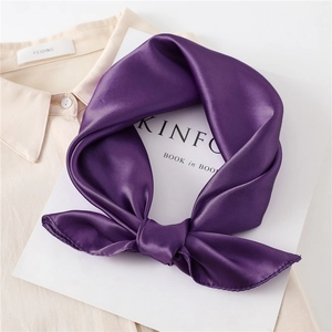 Close-up of deep purple satin square scarf tied in a bow showing glossy silk texture