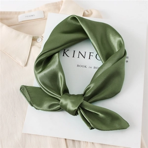 Close-up of a dark green satin silk scarf with a glossy finish on a white magazine