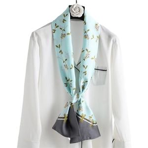 Narrow floral silk scarf in mint green draped on a shirt for a stylish spring look