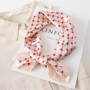 Elegant pink plaid satin silk scarf with red and blue geometric patterns on a magazine
