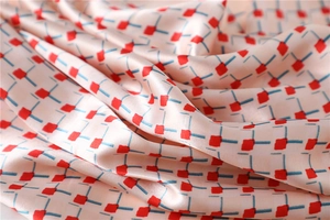 Close-up of pink satin scarf with geometric pattern and elegant soft fold texture