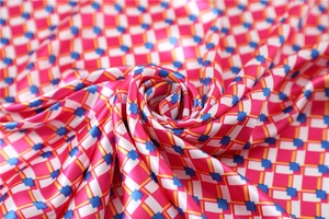 Macro view of silky satin square scarf with geometric plaid pattern in rose and blue