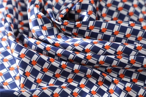 Macro shot of plaid satin neckerchief featuring navy blue, white and orange geometric patterns
