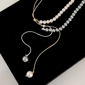 Adjustable pearl necklaces in white and grey with gold and silver chains on black velvet