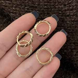 Créoles dorées minimalistes avec rayures en émail marron sur un fond en maille confortable