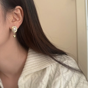 Boucles d'oreilles vintage avec pendentif coeur et perles portées par un mannequin