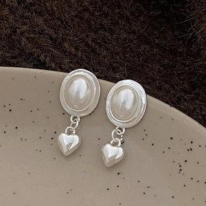 Gros plan de boucles d'oreilles cœur vintage avec perles sur une plaque céramique