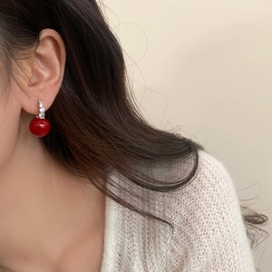 Detailaufnahme von eleganten roten Perlenohrringen mit silbernen Steckern an einem Modell