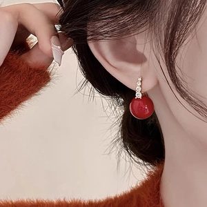 Elegante rote Perlenohrringe mit Kristallsteckern und Goldakzenten am Modell
