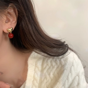 Elegant red pearl heart dangle earrings in gold finish worn by a female model