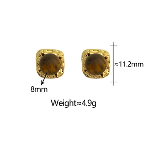Détail de boucles d'oreilles dorées avec œil de tigre et texture métallique martelée