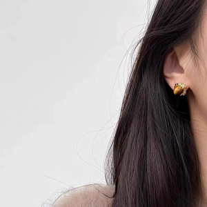 Détail macro de boucles d'oreilles gland avec pierre œil de tigre sur base dorée