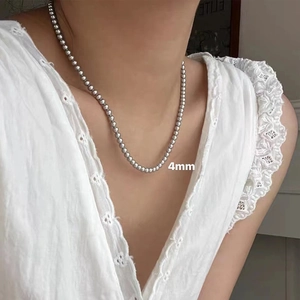 Detailed view of a 4mm silver bead chain necklace worn on the collarbone for styling