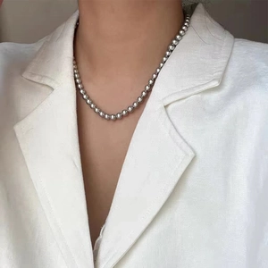 Close-up of polished silver bead necklace worn on a neck showing mirror metallic texture