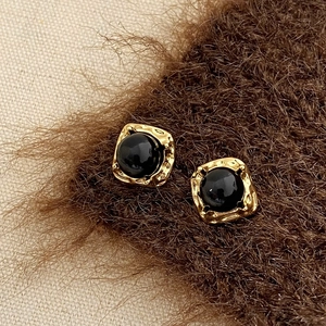 Détails macro de boucles d'oreilles vintage en or martelé avec onyx noir élégant