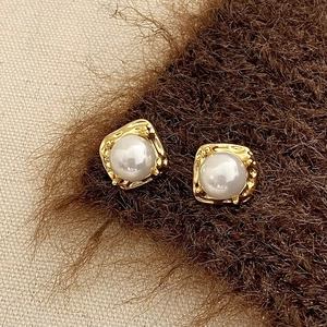 Gros plan de boucles d'oreilles carrées en or martelé avec perle blanche centrale