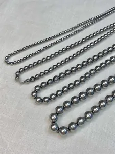Detail of five different sizes of dark grey pearl necklaces with glossy mirror finish