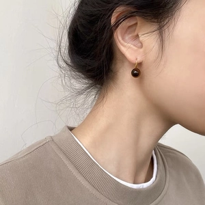 Elegant gold hook earrings with round tiger eye stone bead worn on female model