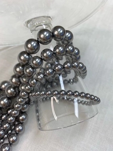 Macro view of dark grey pearl necklace with gradient sizes on a glass base