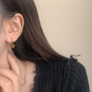 Detailed shot of retro gold hook earrings with round amber tiger eye stone drops