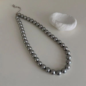 Macro detail of grey pearl necklace showing silver extender chain and smooth round pearls