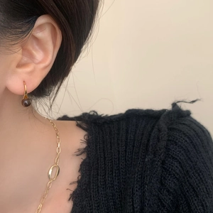 Close-up of vintage tiger eye drop earring with golden hook on model with necklace