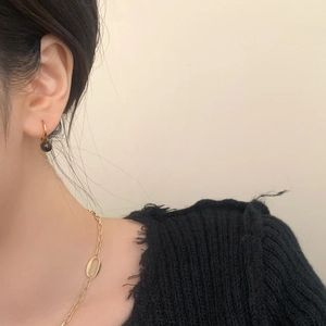 Detail of vintage tiger eye drop earrings and gold link necklace on a model
