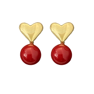 Elegant gold heart stud earrings with round red pearl drops on white background