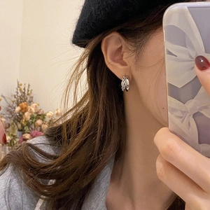 Gros plan de boucles d'oreilles doubles anneaux croisés en argent sur mannequin