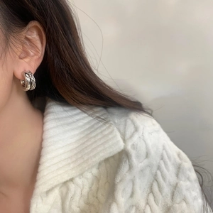 Gros plan de boucles d'oreilles doubles argentées torsadées portées par un mannequin
