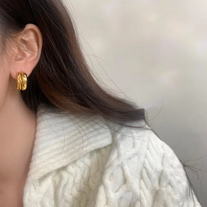 Gros plan détaillé de boucles d'oreilles créoles dorées à double rangée avec maille tressée