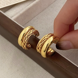 Détails de boucles d'oreilles doubles anneaux dorés avec textures tressées et polies