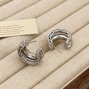 Vue détaillée de boucles d'oreilles créoles torsadées en argent sur velours beige