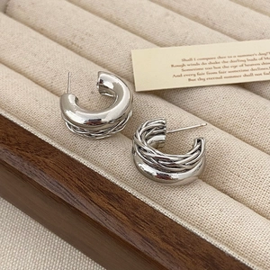 Détail de boucles d'oreilles créoles double couche argentées avec texture tressée fine