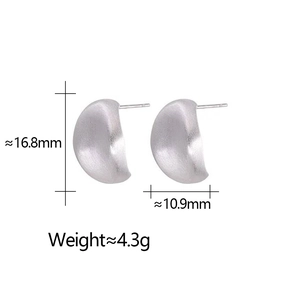 Dettaglio macro di orecchini in argento opaco con finitura spazzolata e design emisferico