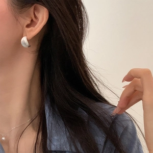 Orecchini a perno a C in argento spazzolato e collana di perle su modella femminile