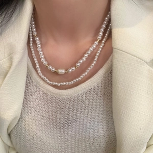 Détail d'un collier de perles d'eau douce double rang avec accents dorés et perle baroque
