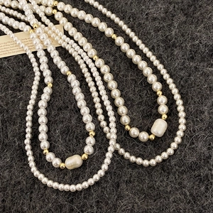 Collier double rang en perles d'eau douce avec détails dorés et perle baroque sur peluche