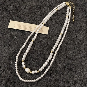 Collier double rang de perles d'eau douce avec fermoir doré sur fond texturé élégant