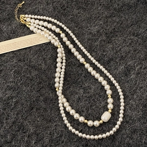 Détail de collier de perles d'eau douce multicouche avec perles dorées sur feutre gris